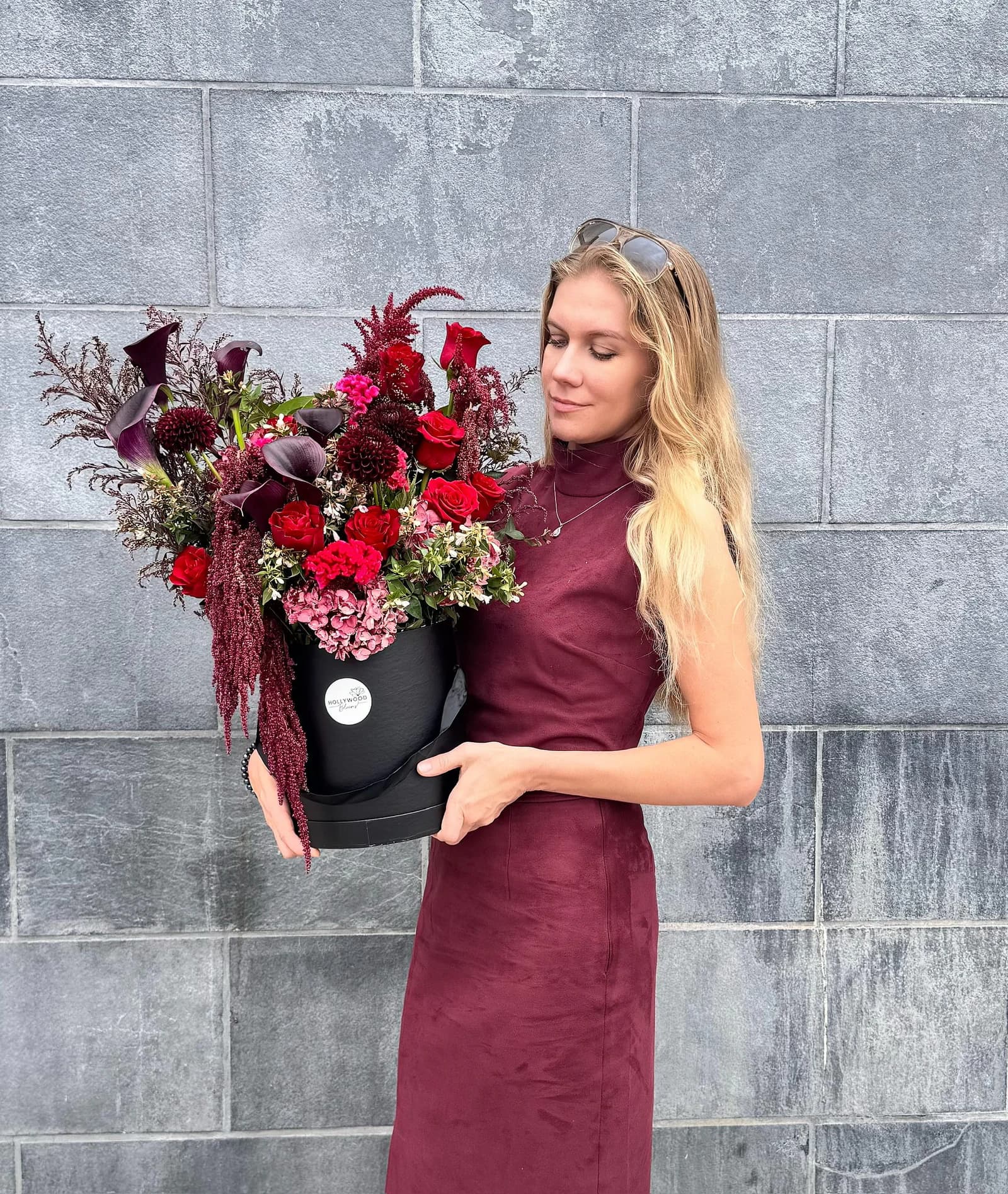 Woman holding a dramatic burgundy floral arrangement by Hollywood Blooms